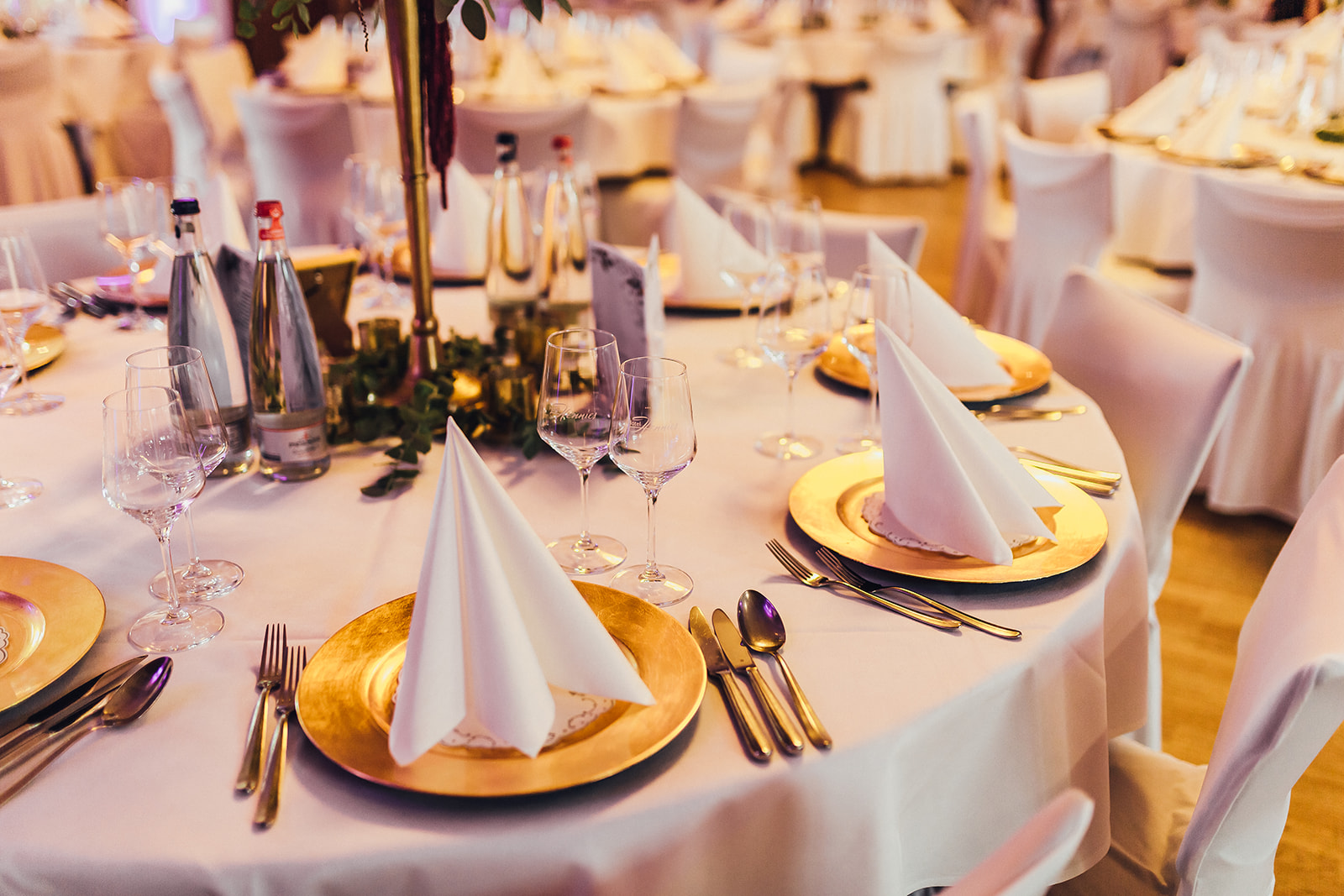 Für eine Hochzeit gedeckter Tisch mit goldenen Tellern im Hotel Hennies.
