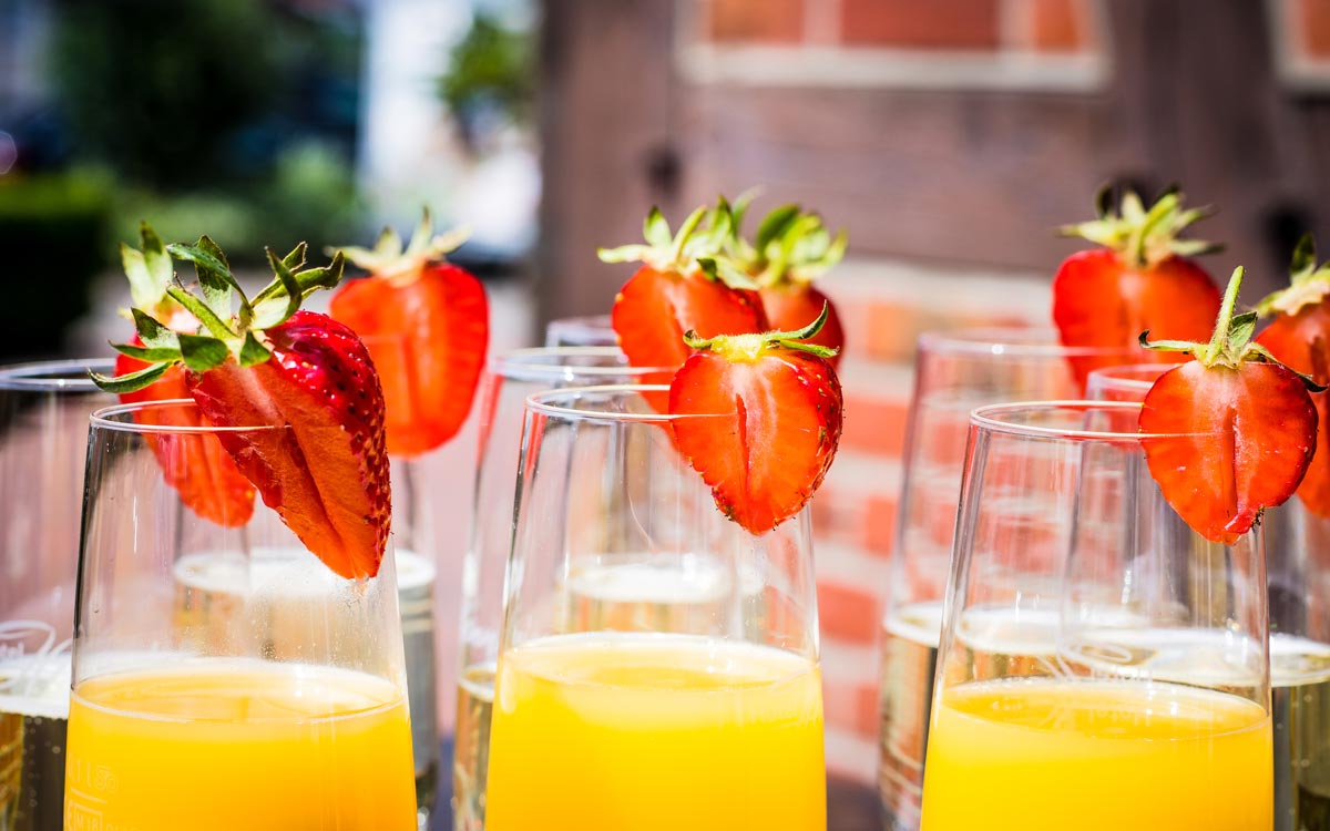 Sekt- und Orangensaftgläser dekoriert mit Erdbeerscheiben für einen Empfang während einer Veranstaltung im Hotel Hennies