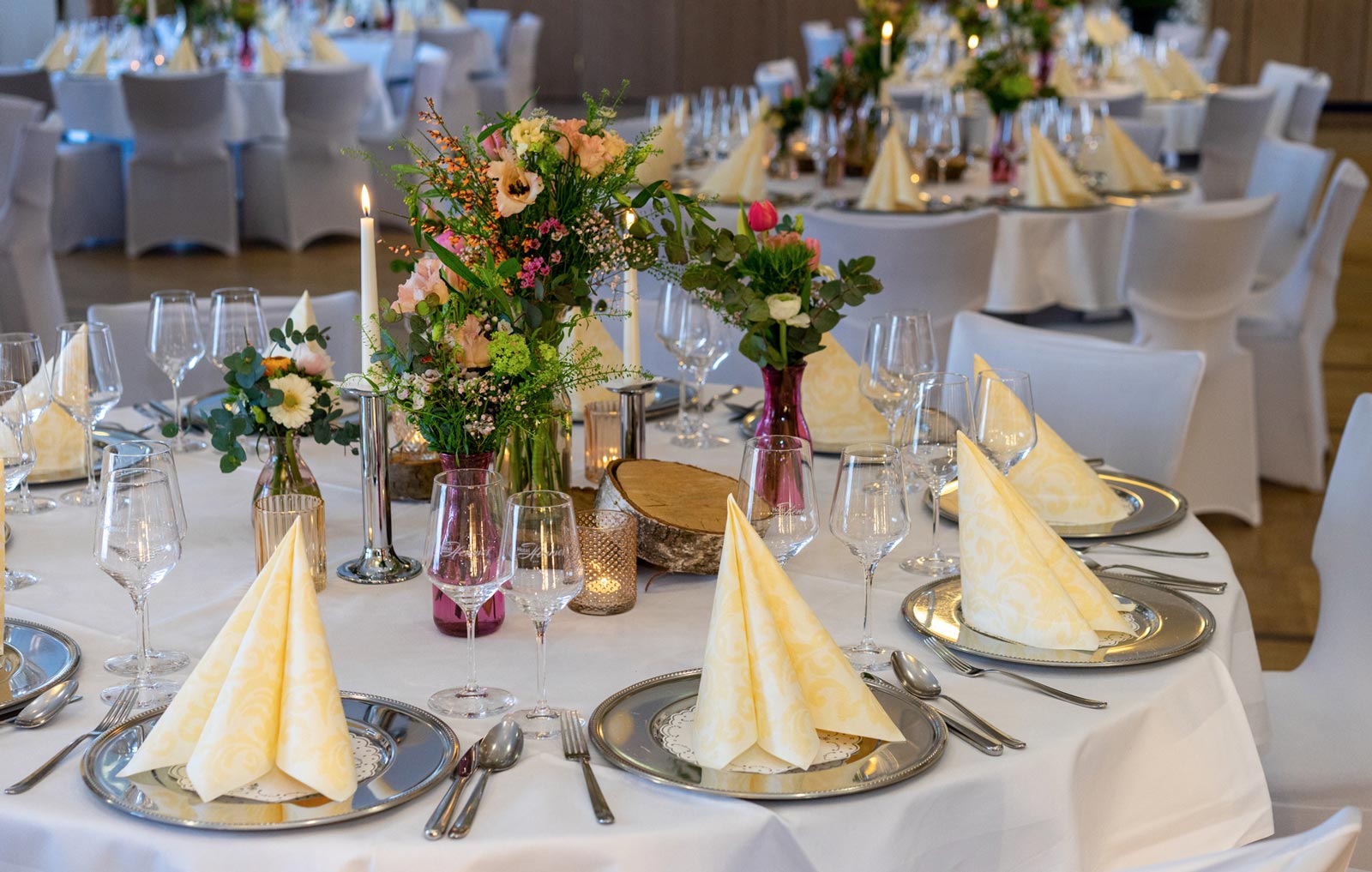 Gedeckter Hochzeitstisch mit silber Tellern und gelben Servietten im Hotel Hennies Landhaus in Isernhagen / Hannover.