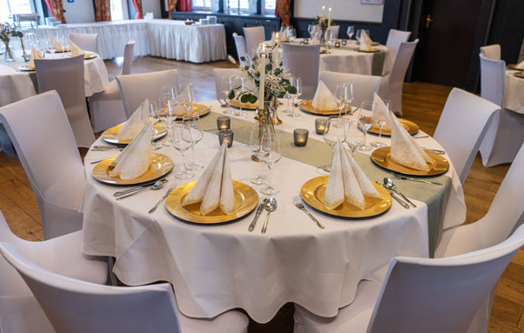 Gedeckter Tisch mit goldenen Tellern und Dekoration für eine Hochzeit in der Eventlocation Hotel Hennies Tenne.