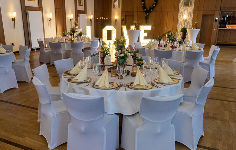 Für eine Hochzeit gedeckte und dekorierte Tische in den Räumen des Hotel Hennies Landhaus