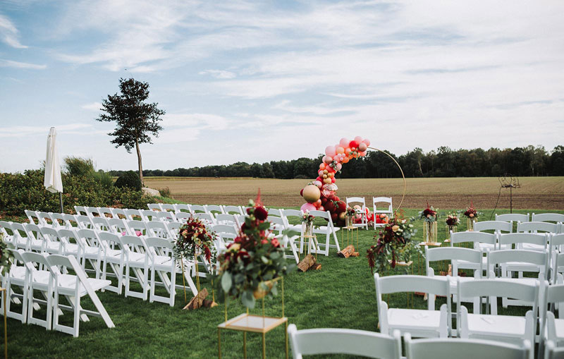 Weiße Stühle in Reihe aufgestellt für die freie Trauung einer Hochzeit im Garten der Eventlocation Hotel Hennies