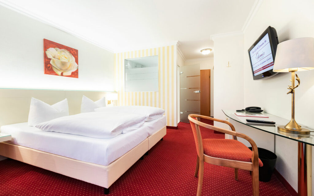 Doppelzimmer im Hotel Hennies in Isernhagen / Hannover: bequemes Doppelbett und ein Schreibtisch in eine hell eingerichteten Zimmer.