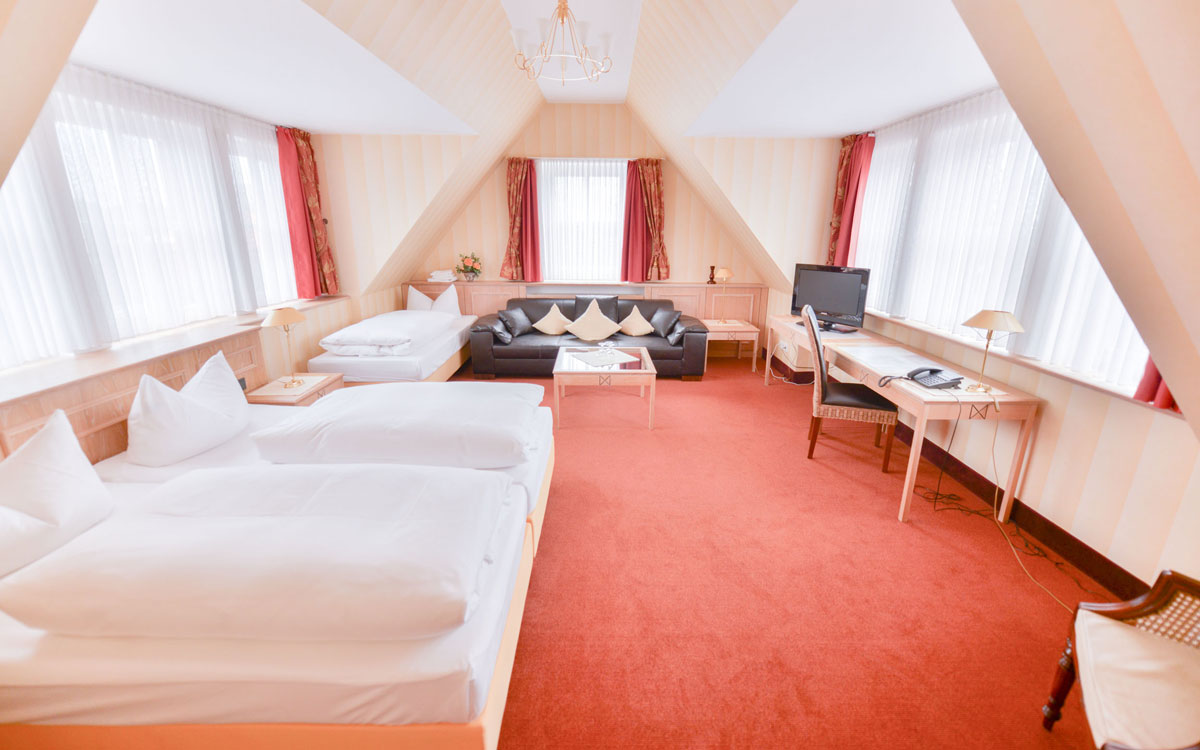 Einblick in eine der Suiten im Hotel Hennies mit drei Betten.