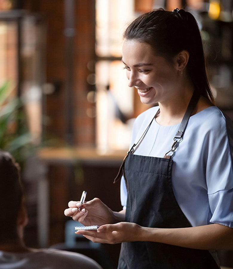 Servicemitarbeiterin nimmt die Bestellung eines Gastes im Restaurant des Hotel Hennies auf